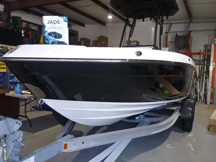 White and black boat hull on a trailer in a workshop during ceramic coating