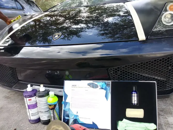 Black exotic car with ceramic coating bottles and certificate laid out in front