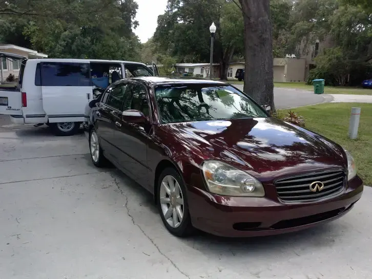 The same maroon sedan with glossy paint after correction