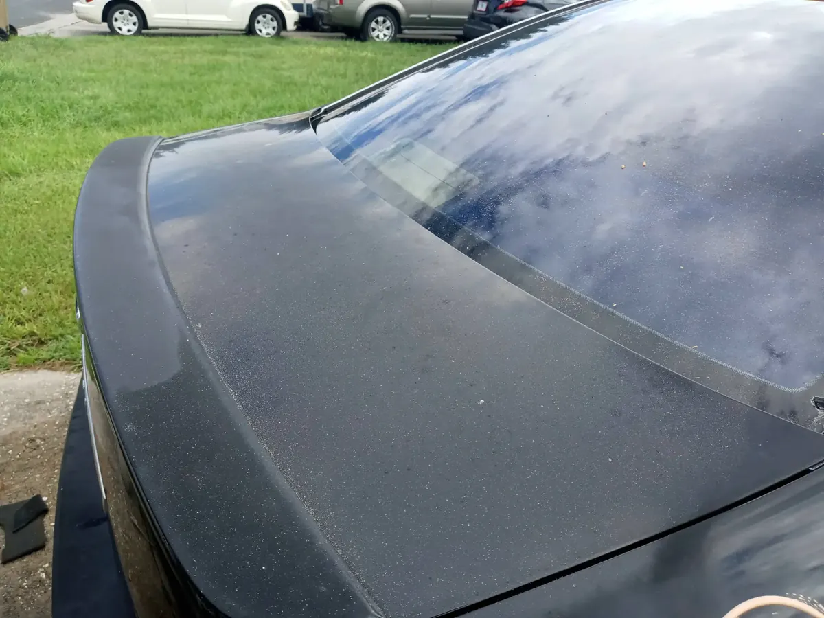 Dark hood with chalky, oxidized paint before polishing