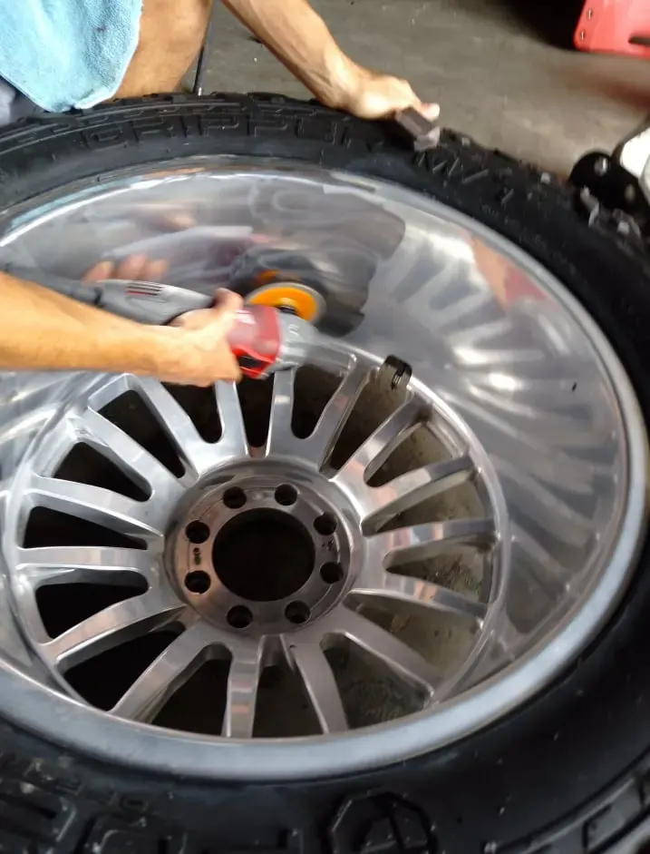Technician hand-polishing an aluminum rim on a tire