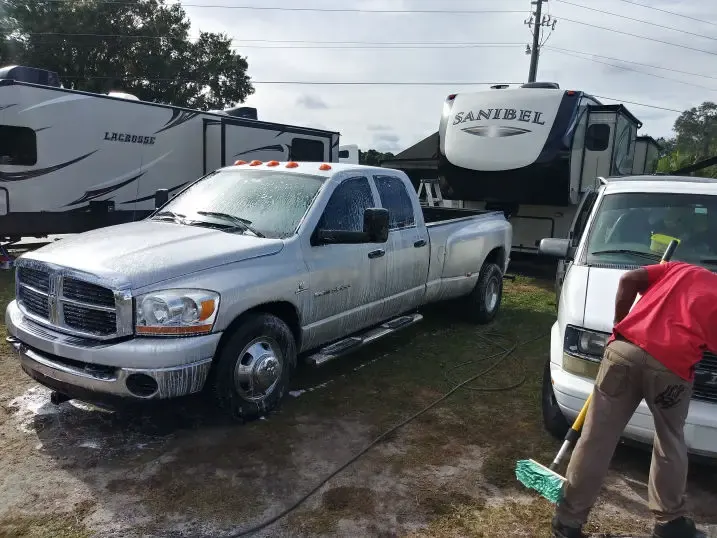 Technician washing a silver pickup truck at an RV park