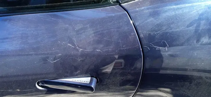 Dark door panel covered in surface scratches