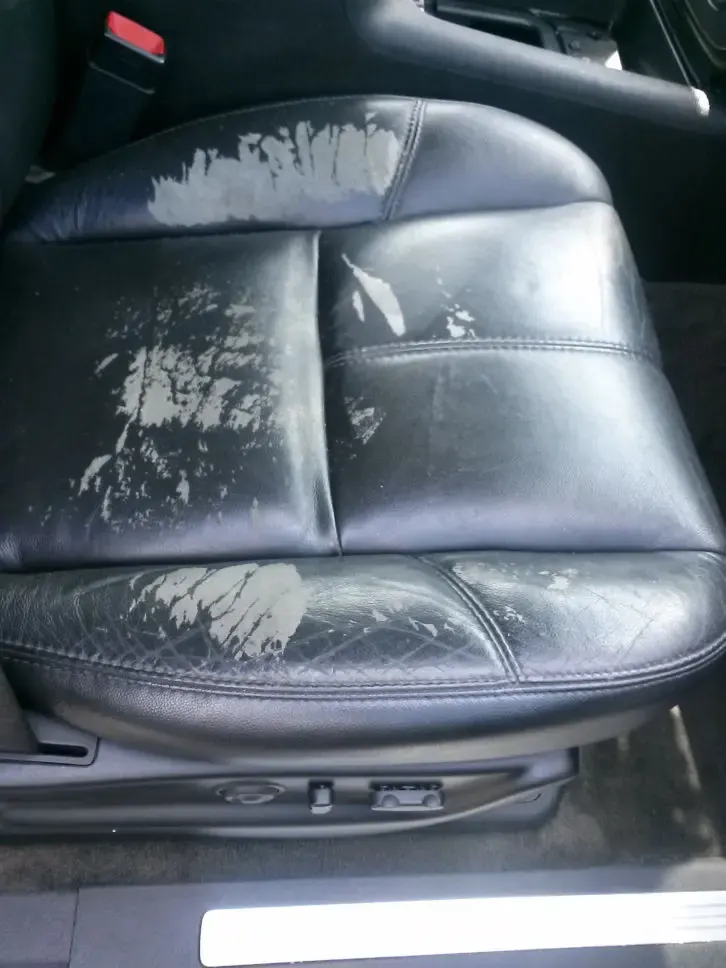 Black leather seat with faded, worn patches before dyeing